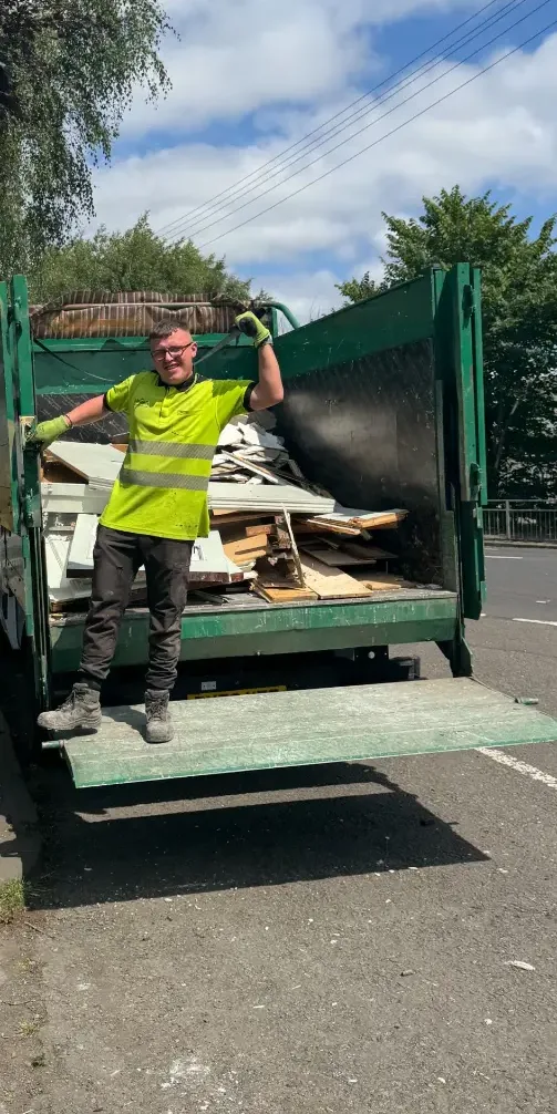 Dumpit crew member on the tail-lift of a lorry loaded with timber and renovation waste